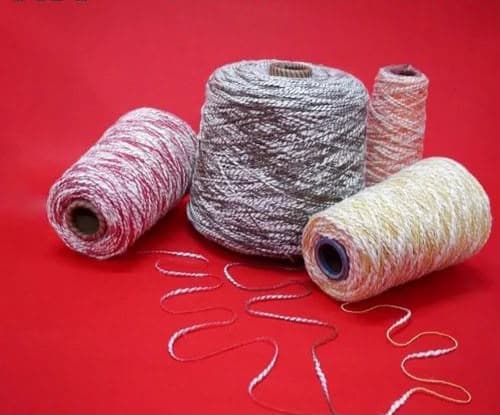 Four spools of variegated yarn in pink, grey, orange, and yellow on a red background.