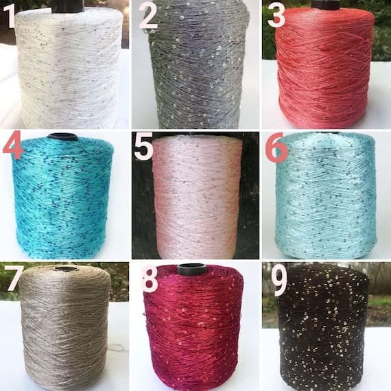 A numbered grid of nine colorful yarn spools, each featuring small, sparkling sequins throughout.